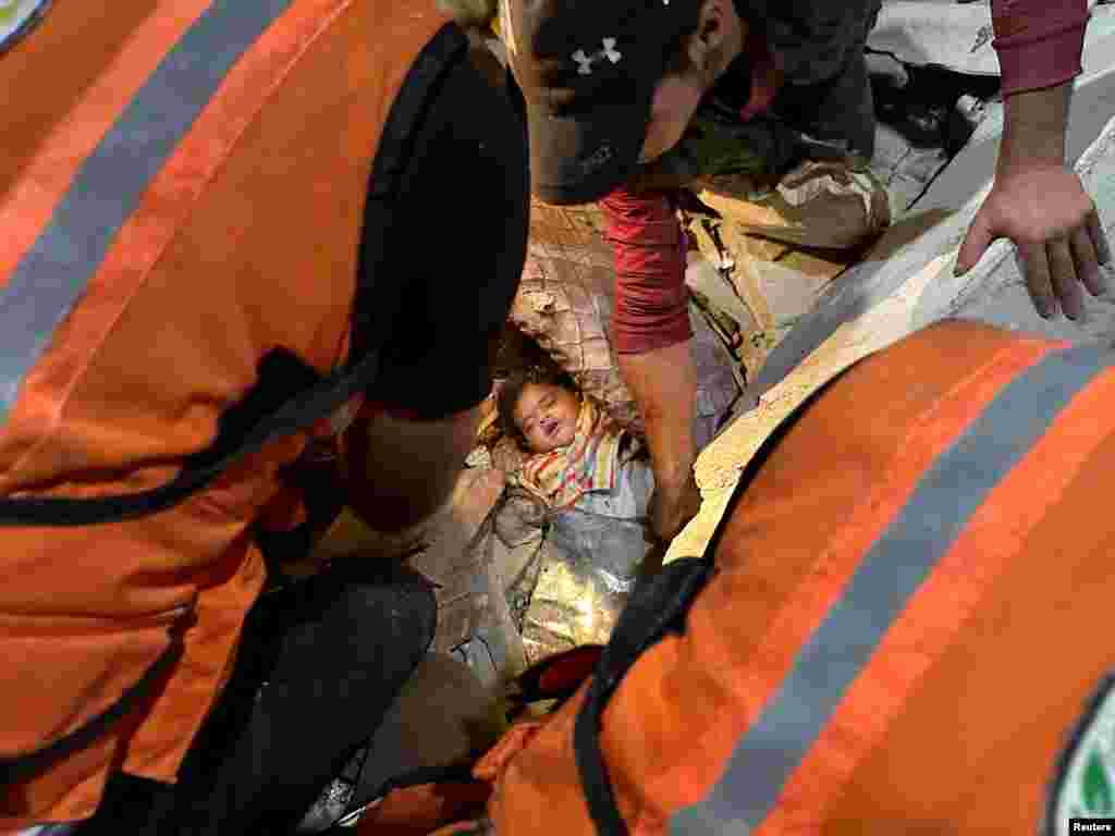 Спасатели помогают вытащить пострадавшего палестинского ребенка из-под обломков дома в Рафахе на юге сектора Газа&nbsp;