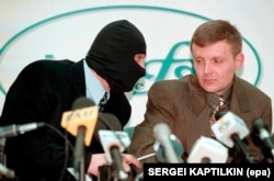 Aleksandr Litvinenko (right) and a colleague wearing a mask to protect his identity are seen at a 1998 press conference in which rebel FSB officers demanded an end to state corruption.