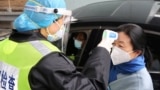 FILE PHOTO: A security officer in a protective mask checks the temperature of a passenger following the outbreak of a new coronavirus, at an expressway toll station on the eve of the Chinese Lunar New Year celebrations, in Xianning, a city bordering Wuhan