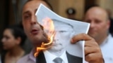 A participant burns a portrait of Russia's President Putin during a rally in Tbilisi
