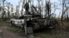 Украинский военный обследует подбитый российский танк под Изюмом в Харьковской области, 11 сентября 2022 года