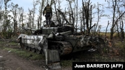 Украинский военный обследует подбитый российский танк под Изюмом в Харьковской области, 11 сентября 2022 года