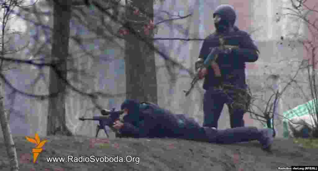 A still photo from a video by RFE/RL&#39;s Ukrainian Service&nbsp;shows Ukrainian security personnel with a Kalashnikov assault rifle and sniper rifle&nbsp;in a confrontation with protesters in Kyiv on February 20, 2014. Dozens of protesters are believed to have been killed by gunfire on this day.