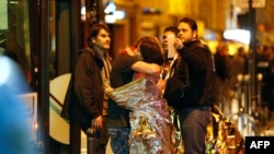 Люди обнимаются на улице возле концертного зала "Батаклан", захваченного боевиками