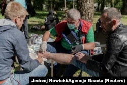 Медики оказывают помощь мужчине, вышедшему из изолятора в Минске, 14 августа 2020 года. Фото: Reuters