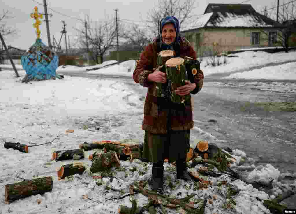 Пожилая украинка несет дрова для обогрева своего дома в подконтрольной Украине Авдеевке на Донбассе (Reuters/Gleb Garanich)
