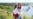 UKRAINE – Happy smiling Ukrainian Mom and daughter in vyshyvanka (embroidered shirts) with a yellow-blue flag on a background of mountains and a river