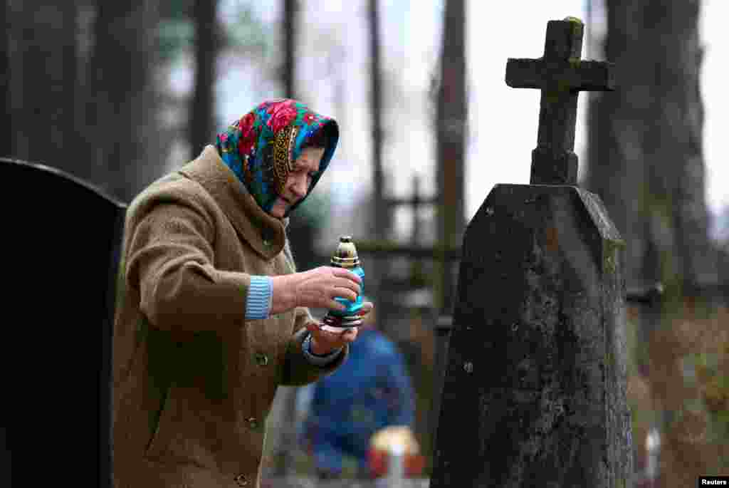 Женщина зажигает свечу на могиле усопшего родственника, Беларусь