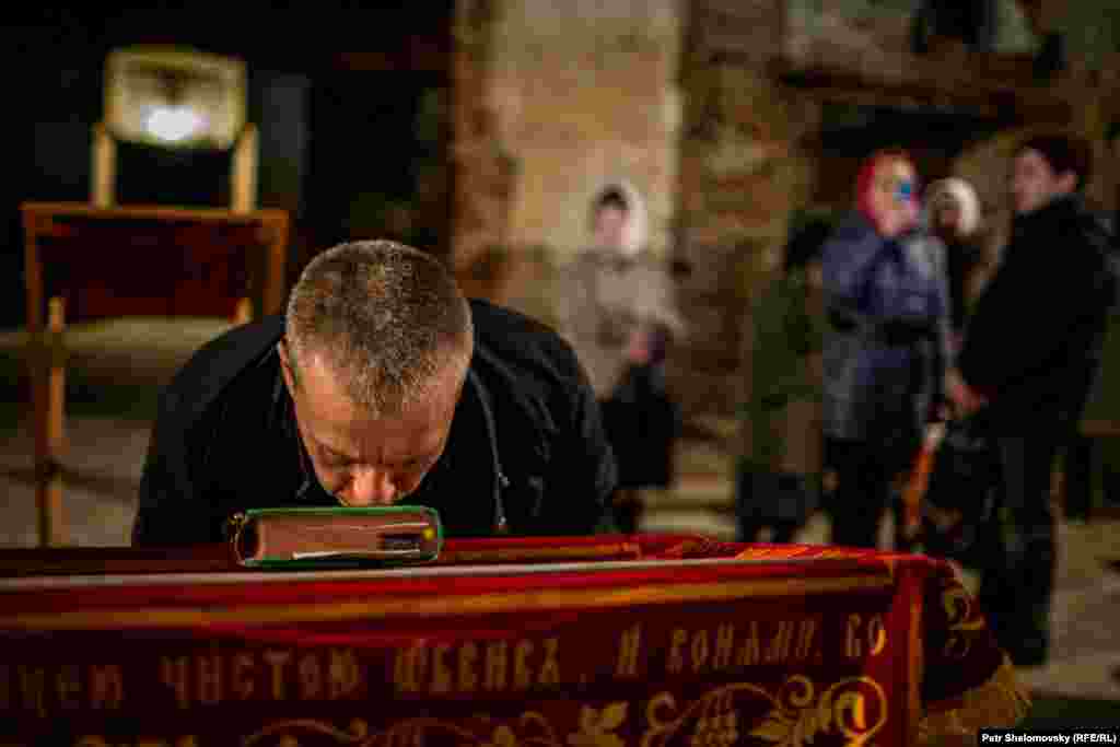 Прихожанин целует Библию в храме в Петровском районе Донецка