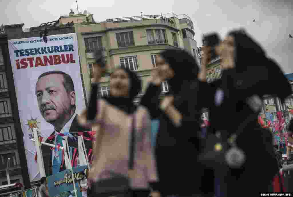 Туристки фотографируются с плакатом турецкого президента Реджепа Эрдогана в день, когда он одержал победу на президентских выборах
