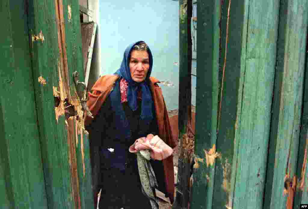 На фото &ndash; пожилая женщина покидает дом во время бомбардировки