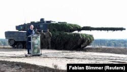 Канцлер Германии Олаф Шольц произносит речь на фоне танка Leopard 2 во время визита на военную базу. Берген, Германия, 17 октября 2022 года. Фото: Reuters