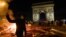 FRANCE -- A yellow vest (Gilets jaunes) protestor gestures as others add to burning material near The Arc de Triomphe on the Champs Elysees in Paris, on November 24, 2018, during a rally against rising oil prices and living costs. - Security forces in Par