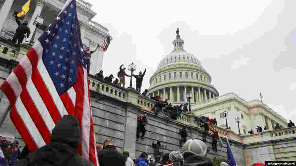 Сторонники Дональда Трампа взбираются на стены Капитолия во время акции протеста против утверждения Конгрессом США результатов президентских выборов&nbsp;