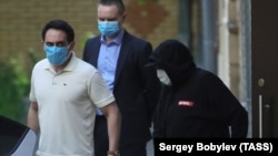 Михаил Ефремов (справа, в капюшоне и маске) 9 июня 2020 года выходит из подъезда своего дома перед допросом в полиции. Фото: ТАСС