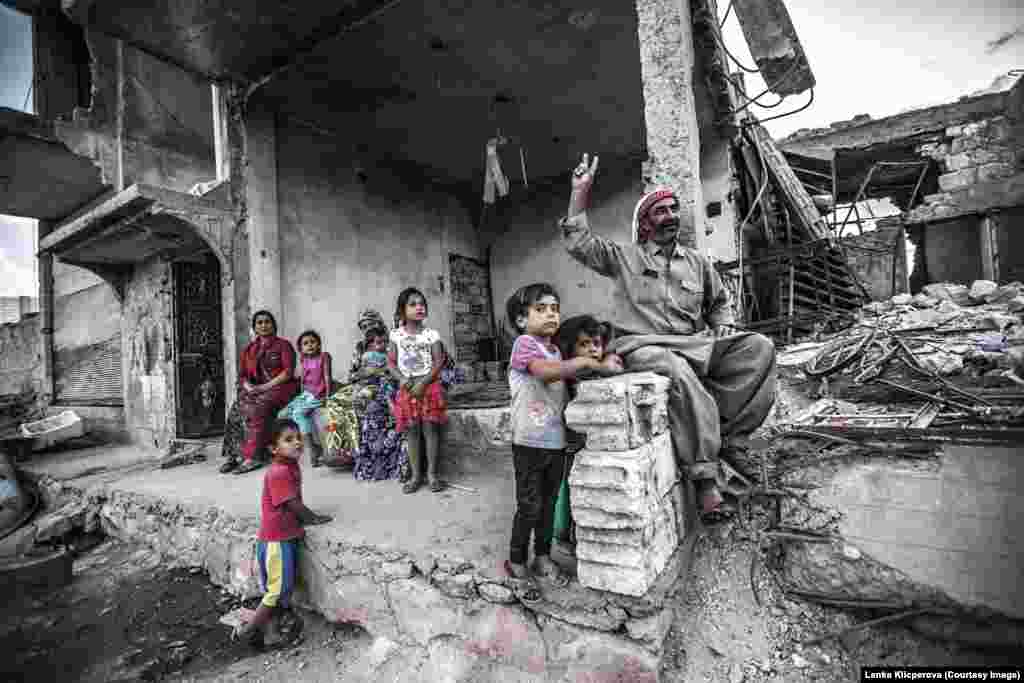 Житель Кобани Джалал Мисто вместе с семьей напротив своего разрушенного дома
