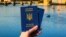Generic – Woman's hand holding two Ukrainian passports in front of Prague old town cityscape
