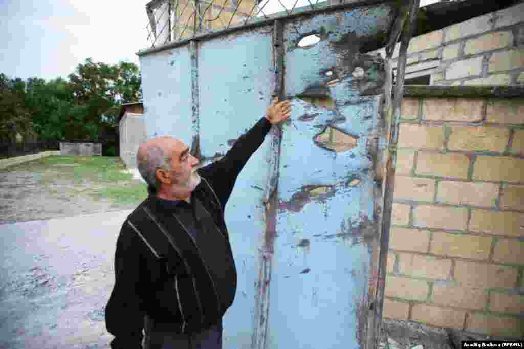 A resident of the Azerbaijani town of Tartar, roughly 52 kilometers north of Nagorno-Karabakh, shows holes in his house&rsquo;s gates, damaged by shelling.
