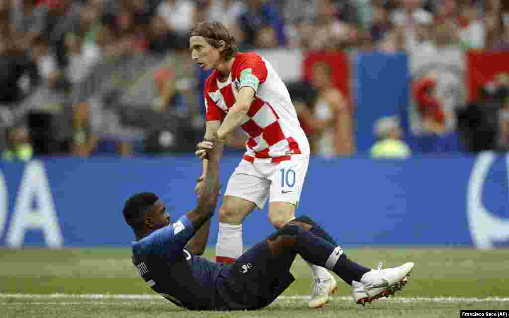 Хорват Лука Модрич помогает встать французскому игроку Самуэлю Умтити во время финального матча