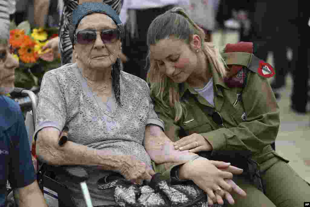 Израильская военнослужащая Шира Тесслер во время церемонии памяти в Иерусалиме держит за руку свою бабушку Ханну Тесслер. На ее руке &ndash; татуировка с номером