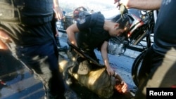 Полицейский оказывает первую помощь избитому толпой солдату, патрулировавшему мост через Босфор