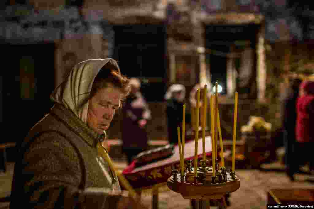 Прихожанка зажигает свечу в храме в Петровском районе Донецка