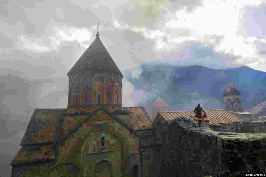 Мужчина с армянским национальным флагом посещает монастырь Дадиванк XII-XIII веков на окраине Кельбаджара в Нагорном Карабахе, 13 ноября 2020 года. Согласно договору о перемирии, эта территория перешла под контроль Азербайджана