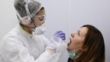 RUSSIA -- A health worker wearing protective gear takes a swab from a woman to test for the coronavirus disease (COVID-19) at Gemotest laboratory in Moscow, April 6, 2020