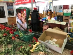 На прилавке, где торговали погибшие, люди оставляют цветы и деньги