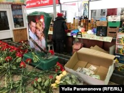 На прилавке, где торговали погибшие, люди оставляют цветы и деньги