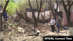 Komil Muminov stands by the ruins of his neighbor's house in the Tajik village of Somoniyon.