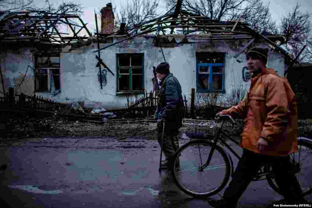 Местные жители проходят мимо разрушенного дома Раисы Казаковой в Дебальцево