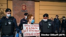 Police officers in Moscow detain Russian photographer Viktoria Ivleva during her May 28 solo protest outside of police headquarters in support of jailed journalist and activist Ilya Azar. "Release Ilya Azar without any fuss," her sign reads. 