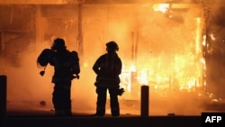 Пожарные пытаются потушить пожар в одном из подожженных зданий в Фергюсоне