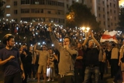 Демонстранты с фонариками в смартфонах возле минской стелы. Ночь с 9 на 10 августа