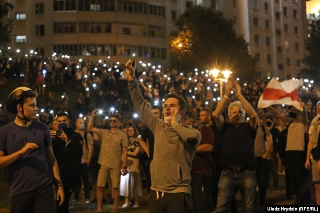 Демонстранты с фонариками в смартфонах возле минской стелы. Ночь с 9 на 10 августа