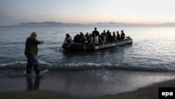 Греческий рыбак помогает вытащить на берег лодку с сирийскими беженцами, май 2015 года 