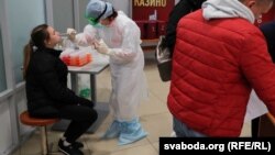 Медработница проводит тестирование на коронавирус у жительницы Беларуси в аэропорту Минска