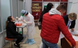 A nurse wearing protective gear takes a swab from a passenger during a coronavirus test at Belarus' Minsk National Airport in March 2020.