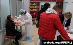 A nurse wearing protective gear takes a swab from a passenger during a coronavirus test at Belarus' Minsk National Airport in March 2020.