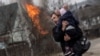Житель города Ирпень с ребенком на руках эвакуируется после обстрела города российскими войсками. 6 марта 2022 года