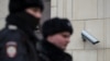 Police officers walk past a surveillance camera in downtown Moscow on January 26, 2020. 