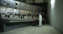 Человек смотрит на покрытый грибком пульт управления на Чернобыльской АЭС