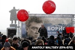 People in St. Petersburg participate in a 2018 memorial event for Boris Nemtsov, seen on the billboard.