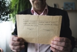 Valery Borshchev shows the paper he was given in 1995, at his home in Moscow on May 29, 2020.