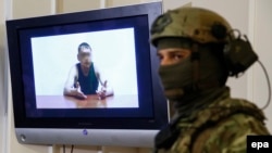 Сотрудник службы безопасности Украины на пресс-конференции стоит рядом с экраном, на котором демонстрируется видеозапись с допросом Владимира Старкова, Киев, 29 июля 2015