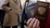 UKRAINE – A woman poses with a Ukrainian and a Russian passport outside an office of the Russian Federal Migration Service, where she received a Russian passport, in the Crimean city of Simferopol, April 7, 2014