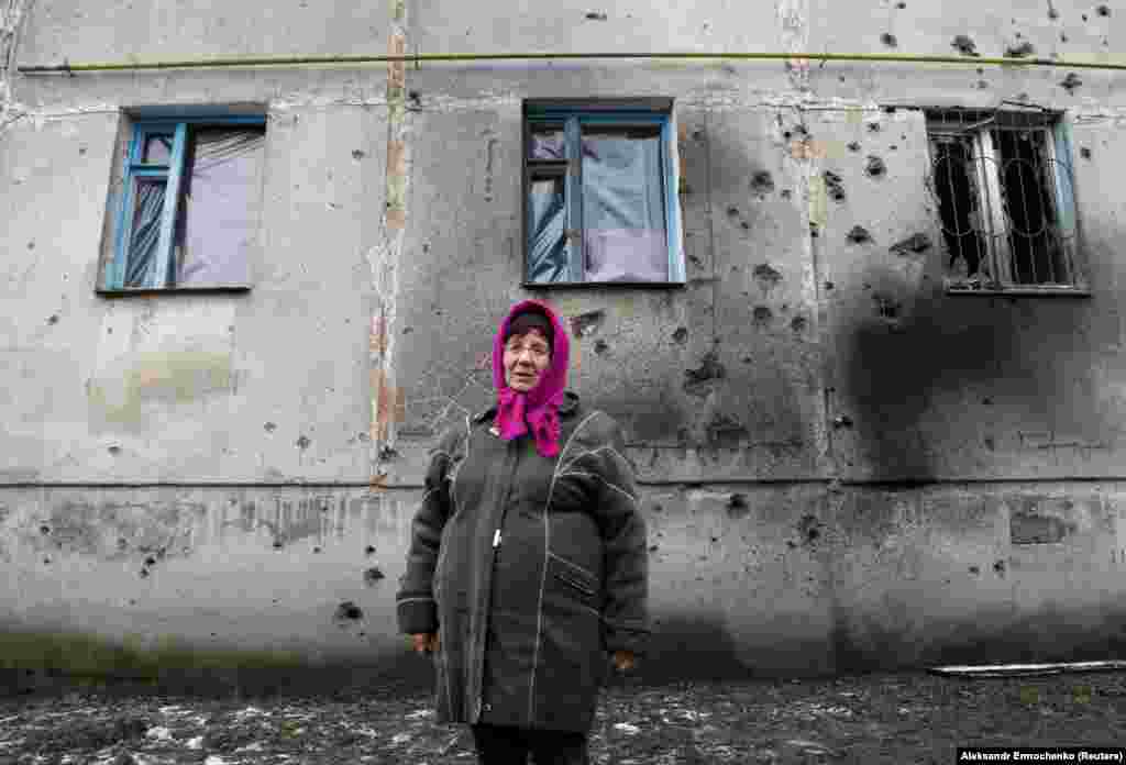 70-летняя местная жительница Лариса Белецкая стоит перед многоквартирным домом, поврежденным во время боев между Вооруженными силами Украины и боевиками поддерживаемых Россией группировок, в поселке Голубовское Луганской области, 19 февраля 2020 года