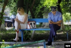 A woman and policeman check their phones while sitting on a bench in downtown Kyiv.