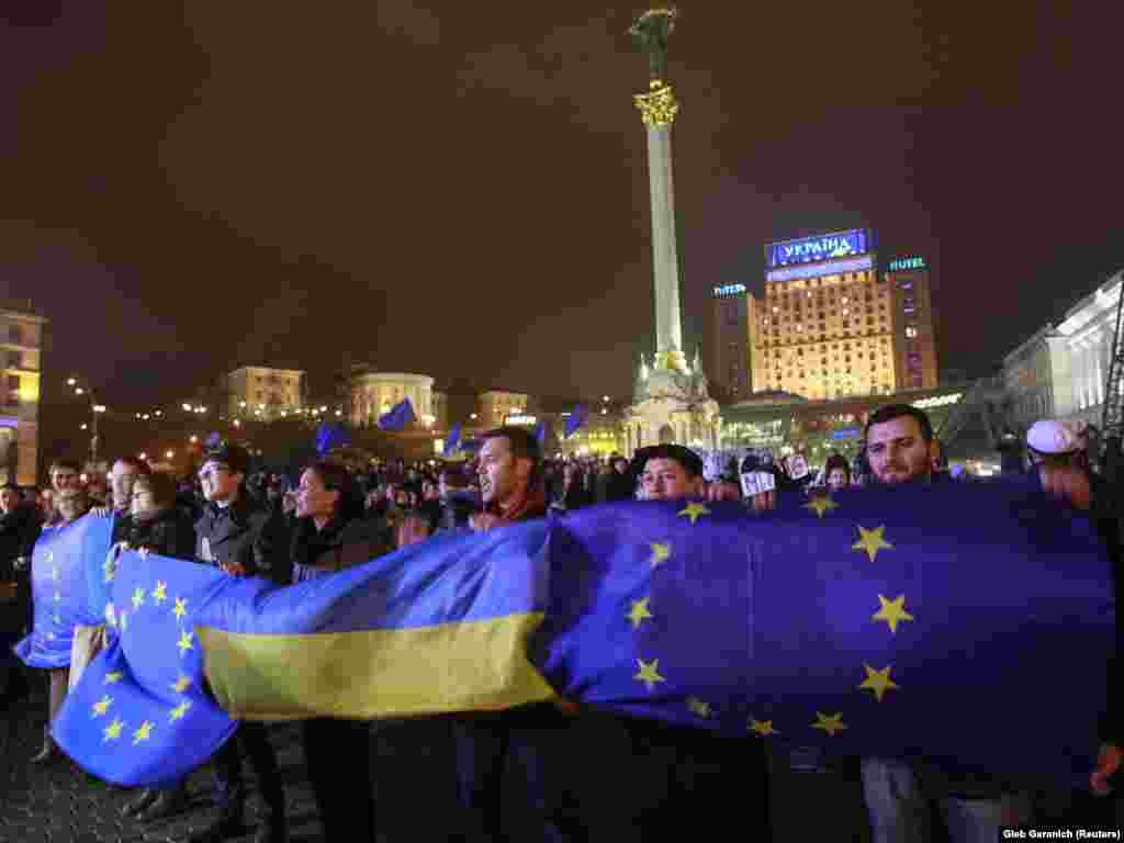 Protesters hold Ukrainian and European Union flags during a rally to support European integration in central Kyiv on November 21, 2013.